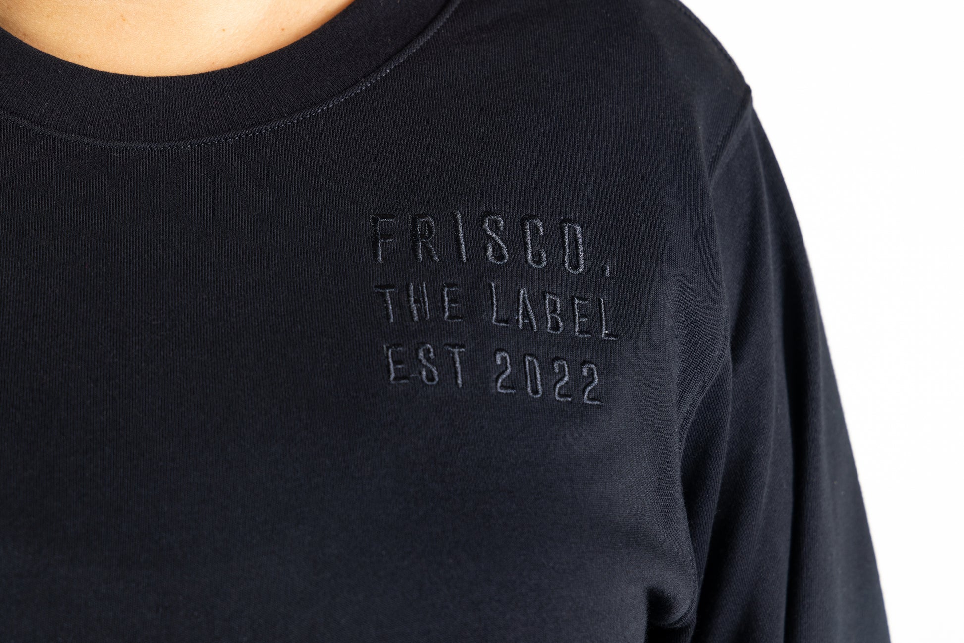 Frisco Women's activewear XL longsleeve crew top in black, extreme closeup of black embroidery on chest that says Frisco, the label, Est 2022