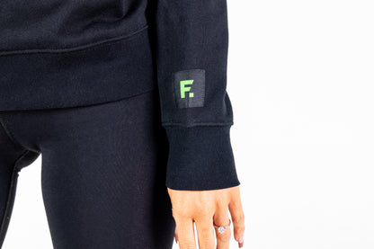 "Frisco Women's activewear small longsleeve crew top in black, closeup of sleeve patch with green Frisco logo "