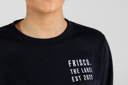 "Frisco Women's activewear small longsleeve crew top in black, closeup of white embroidery on chest that says Frisco, the label, Est 2022 "