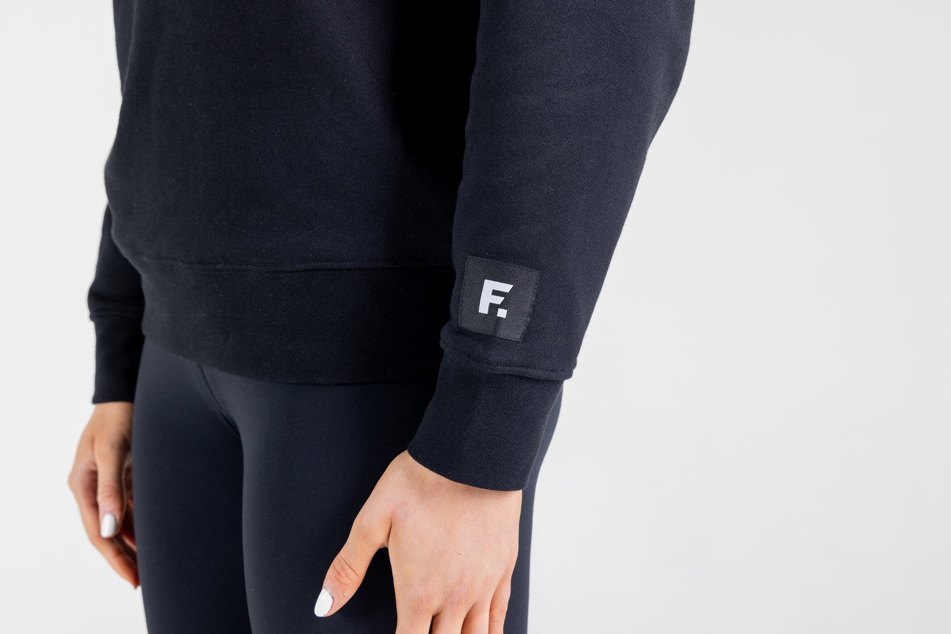 "Frisco Women's activewear small longsleeve crew top in black, closeup of sleeve patch with white Frisco logo "