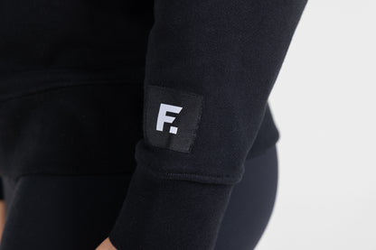 "Frisco Women's activewear small longsleeve crew top in black, extreme closeup of sleeve patch with white Frisco logo "